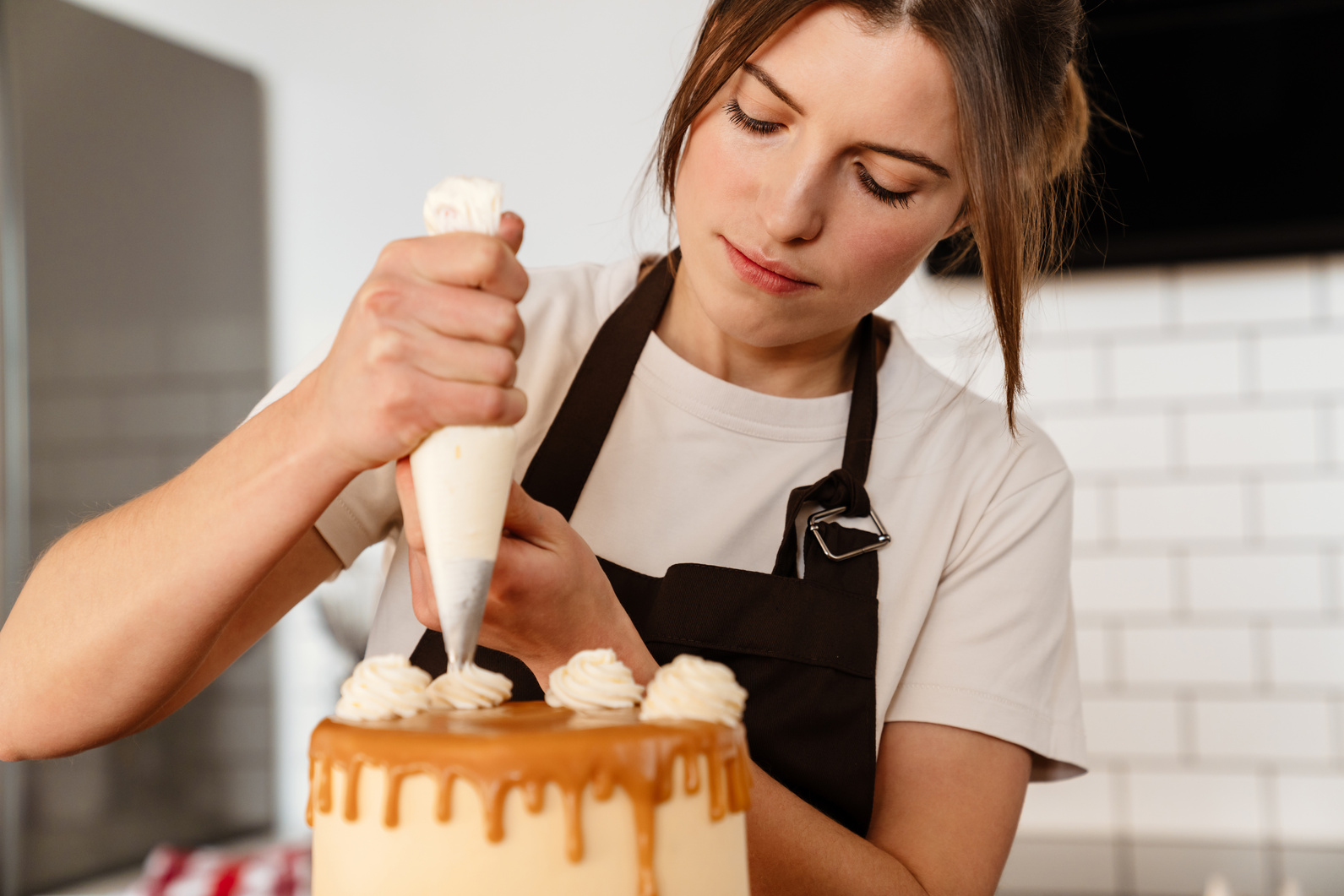 Beautiful Focused Baker Woman Making Cake with Cream in Kitchen at Home